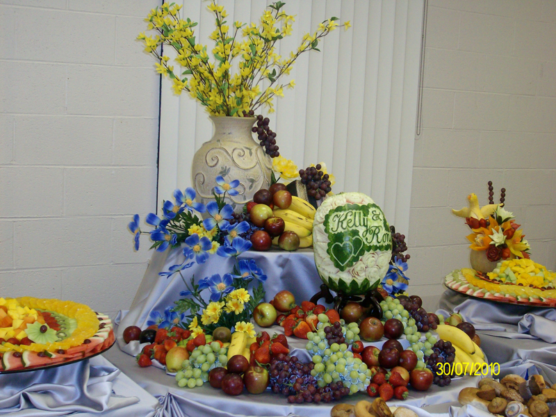 Tiered fruit and charcuterie display on a draped buffet table